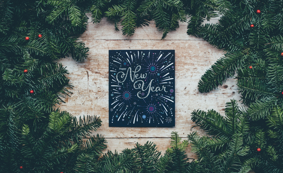 holiday pines with a chalkboard sign in the center that says "New Year"