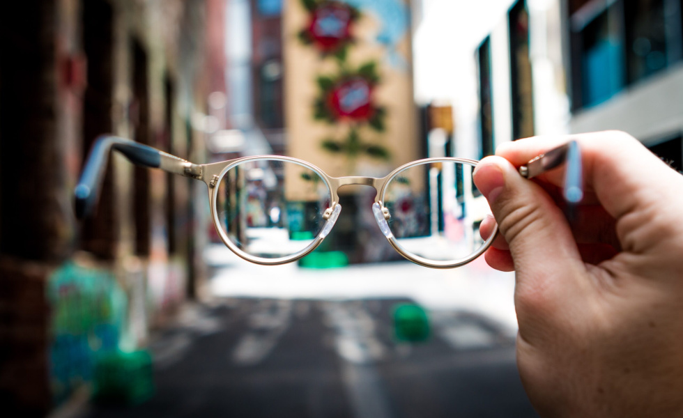 Hand holding glasses were everything around looks blurry through the lenses