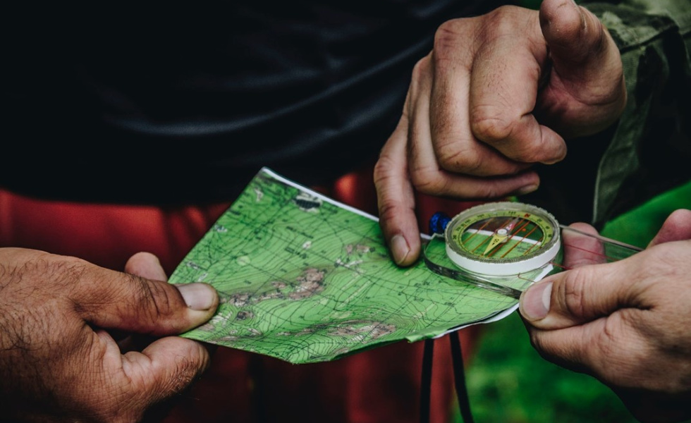 hands holding a map and someone else using a magnifying lens for a closer look