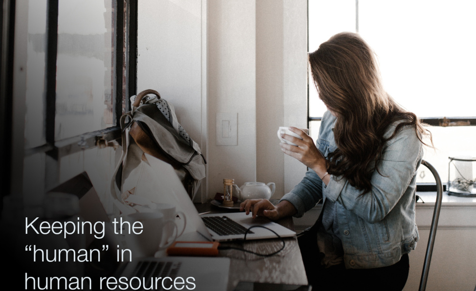 A woman sitting at her desk drinking coffee with text overlaid that says, "Keeping the 'human' in human resources"